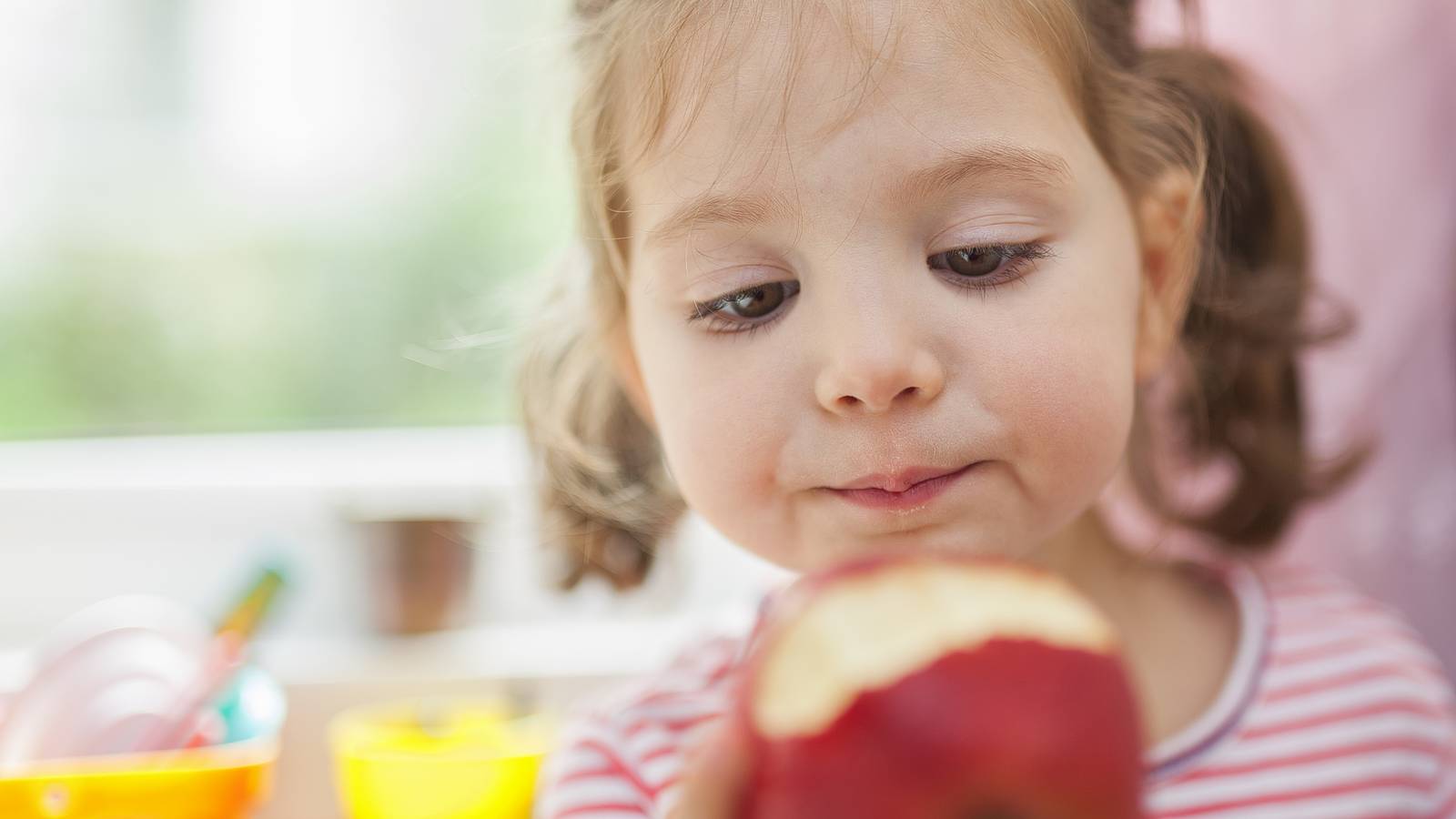 Young girl eating a fruit in a restaurant -- image on Partnership for a Healthier America's website.