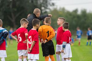 Youth soccer coach gives pep talk to team.