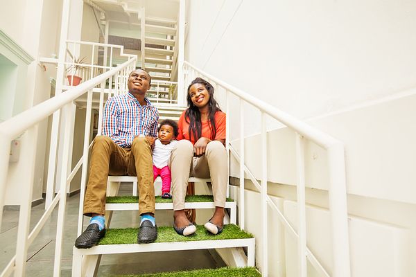 Family sitting on stairs in apartment complex.