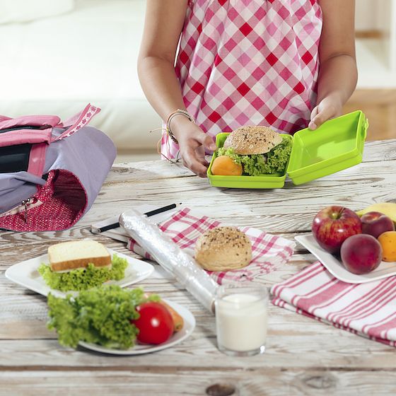 Image of a mom at a kitchen counter preparing food for a child's lunchbox. 
