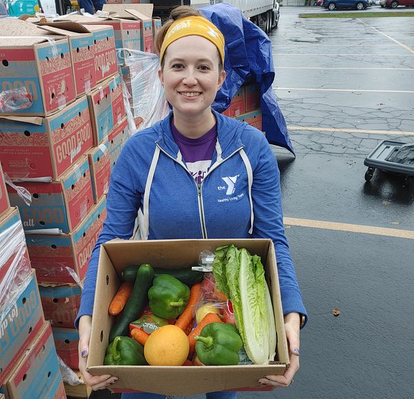 A YMCA volunteer holding a Good Food for All produce box