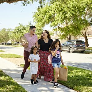Family carrying groceries walking down the street