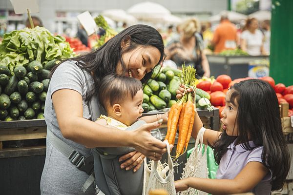Mom and children purchasing vegetables