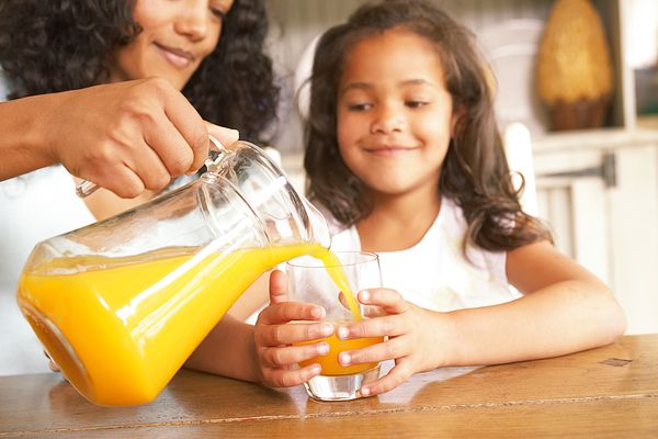 Image of a mom and daughter drinking glasses of orange juice. 