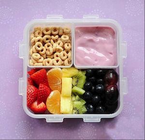 Image of whole grain cereal, yogurt and fruit in a children's lunchbox container. 