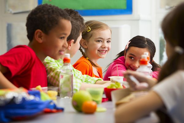 Photo of diverse group of children eating a healthy lunch at school.