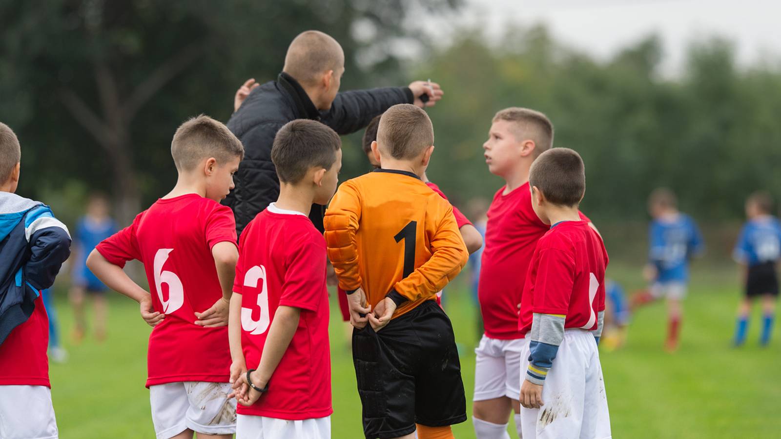 Youth soccer coach gives pep talk to team.
