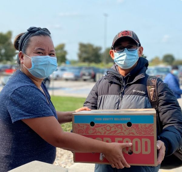 Volunteers holding a red and blue Good Food for All produce box