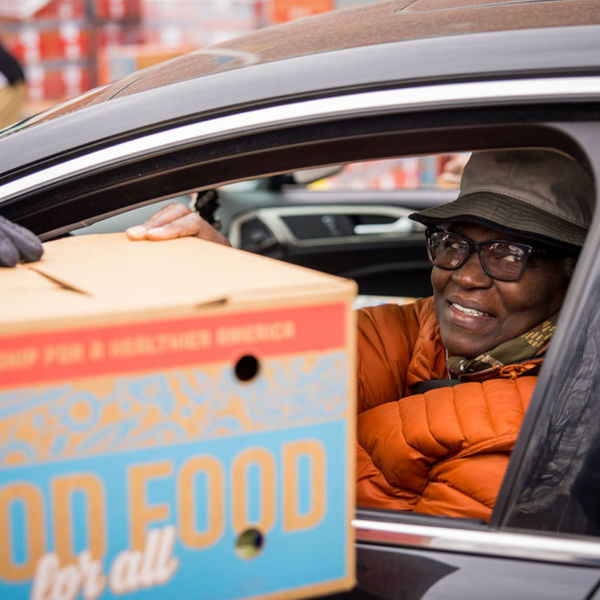 Person receiving a box of food labeled Good Food for All