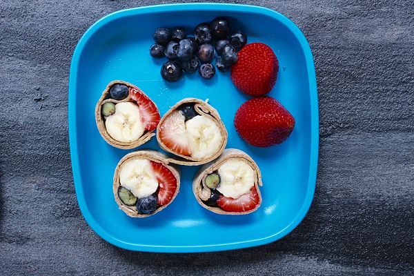 Fruit sushi roll with banana, strawberry and blueberries