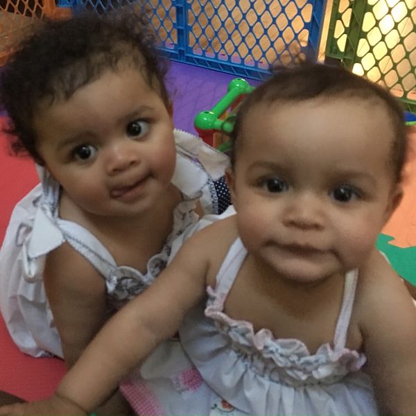 Image of two girls, Gabrielle and Penelope, playing in a play pen at an early child care facility. 