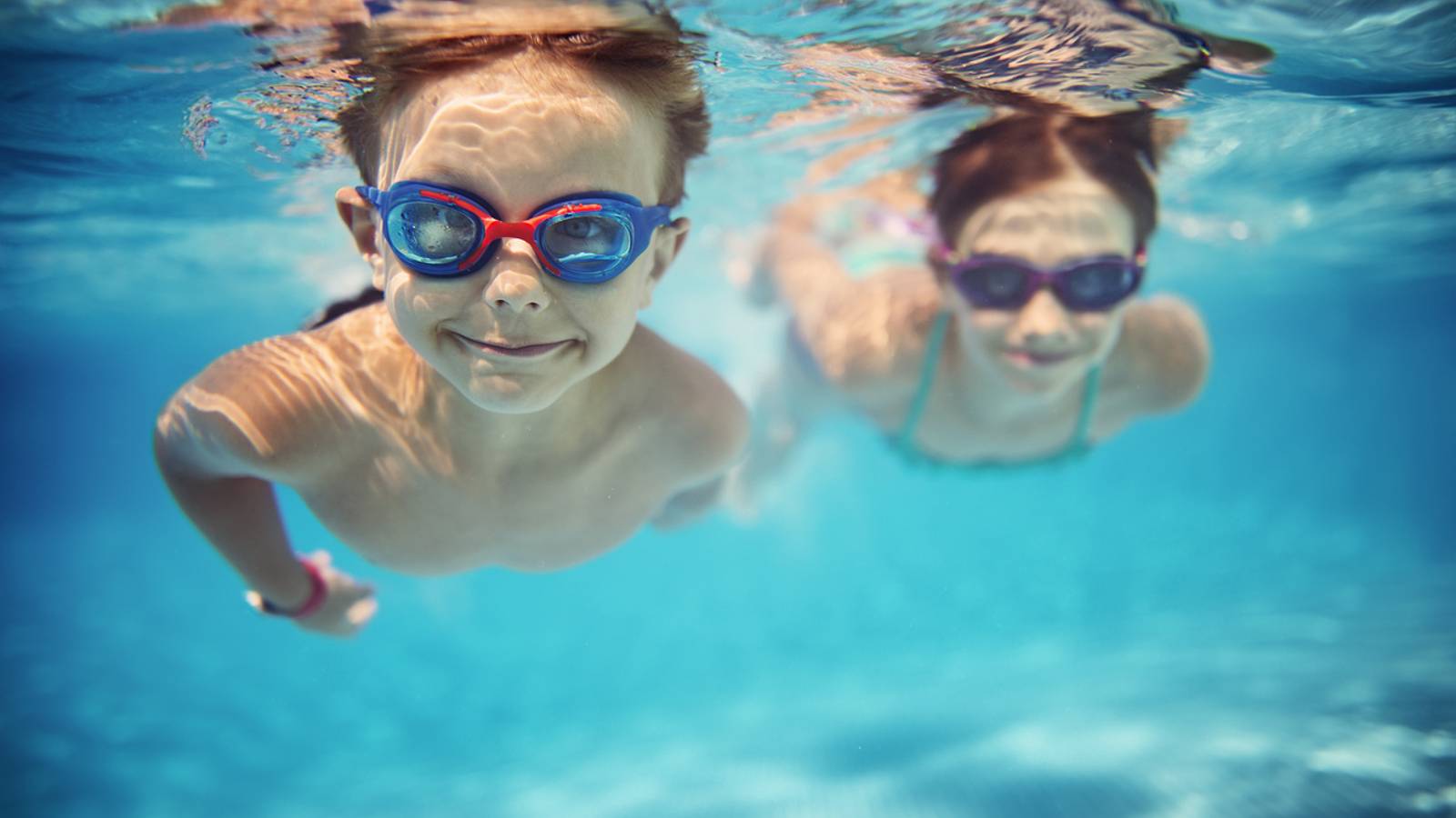 Photo of two children swimming underwater in a pool.