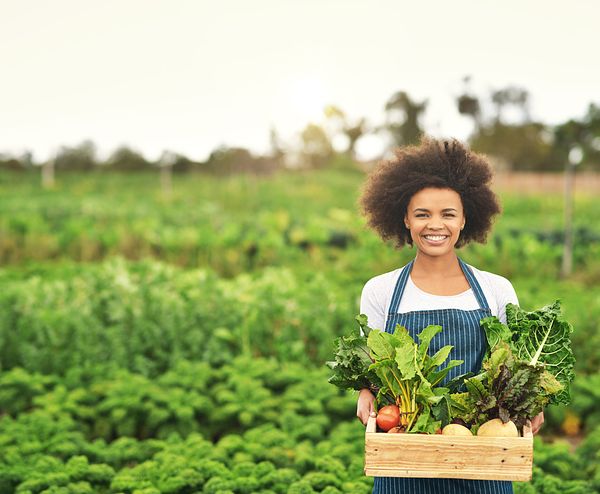 Image of woman farmer holding produce in a basket.