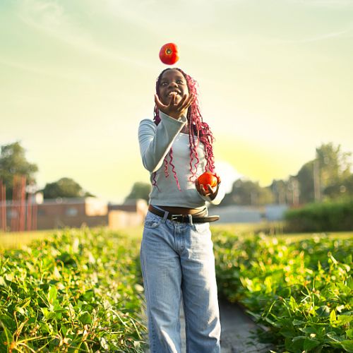 A young girl juggles tomatoes on a Mississippi farm