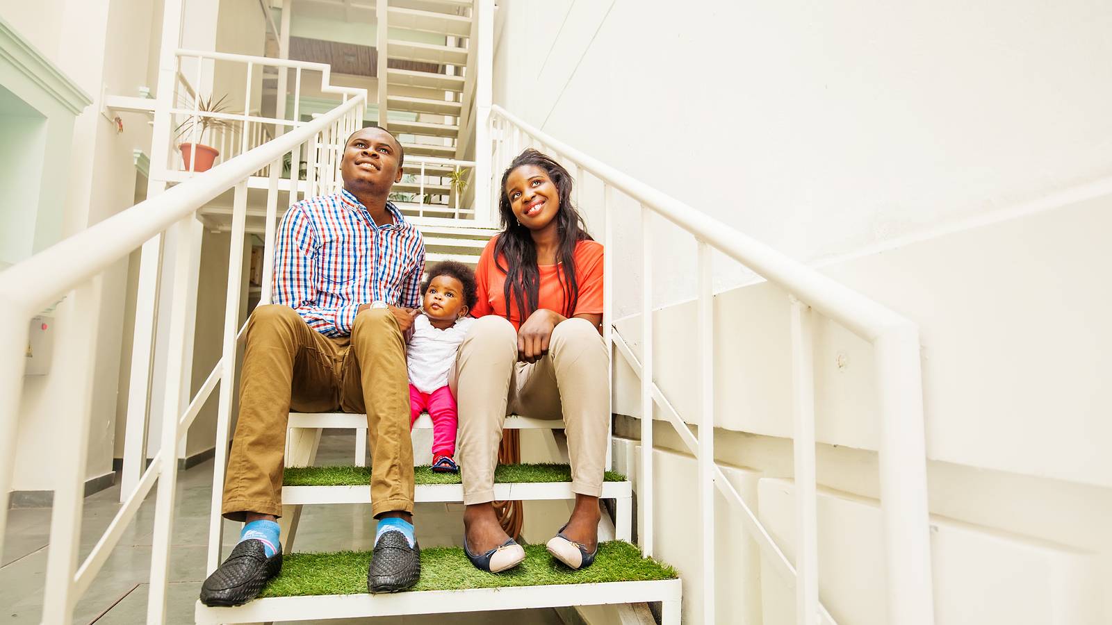 Family sitting on stairs in apartment complex.