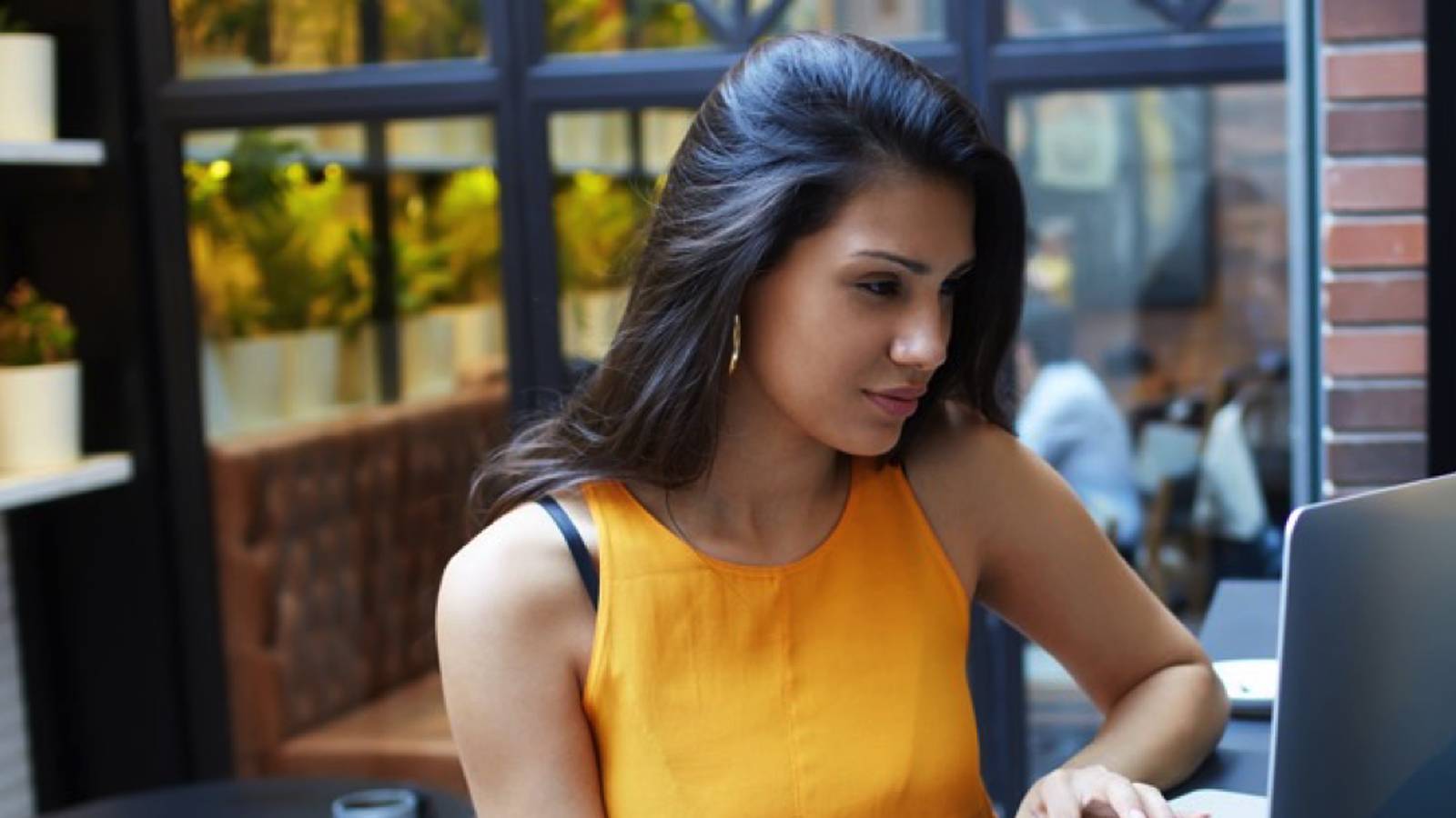 Image of a Latinx college student working on a laptop outdoors. 