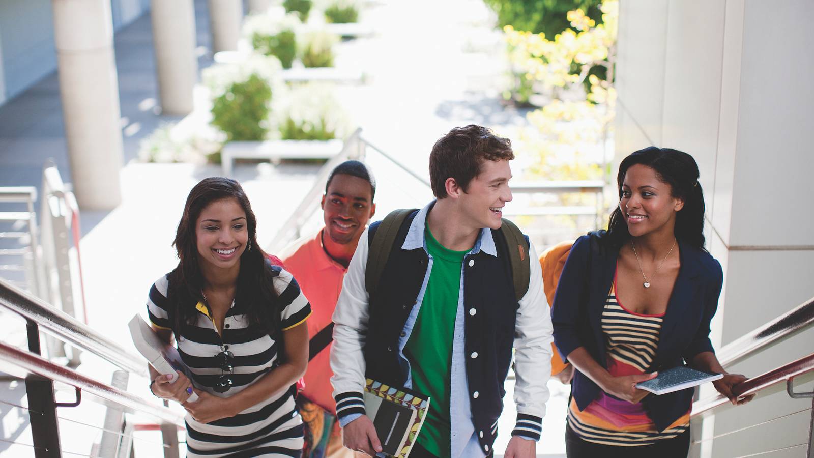 Image of a college student with a laptop on a campus lawn. 