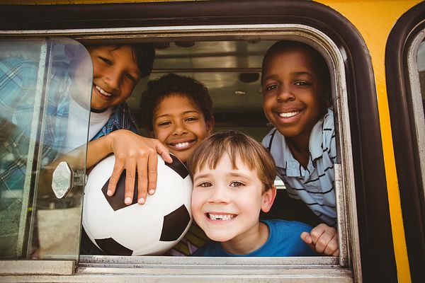 Image of elementary school boys with their heads poking out the window of a yellow school bus. 