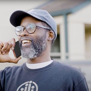 man wearing a baseball cap, on a cell phone