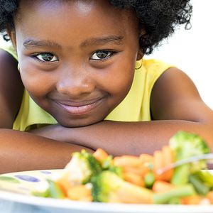 Girl with plate of fruit looking into the camera. 